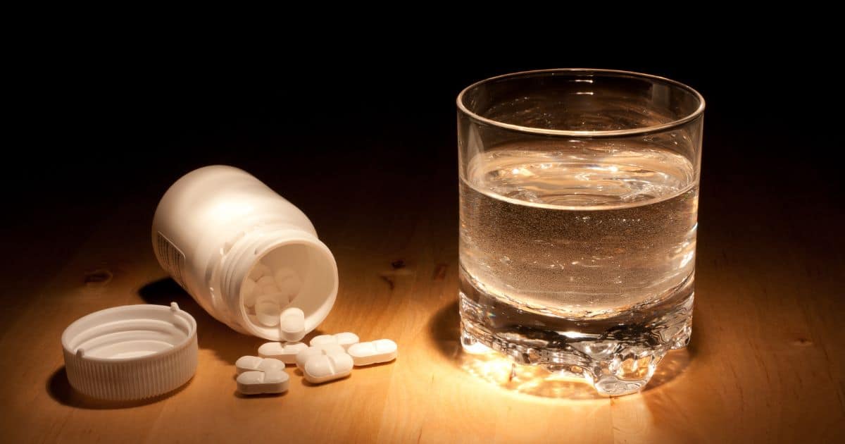 a glass of water stood next to a jar pff pills